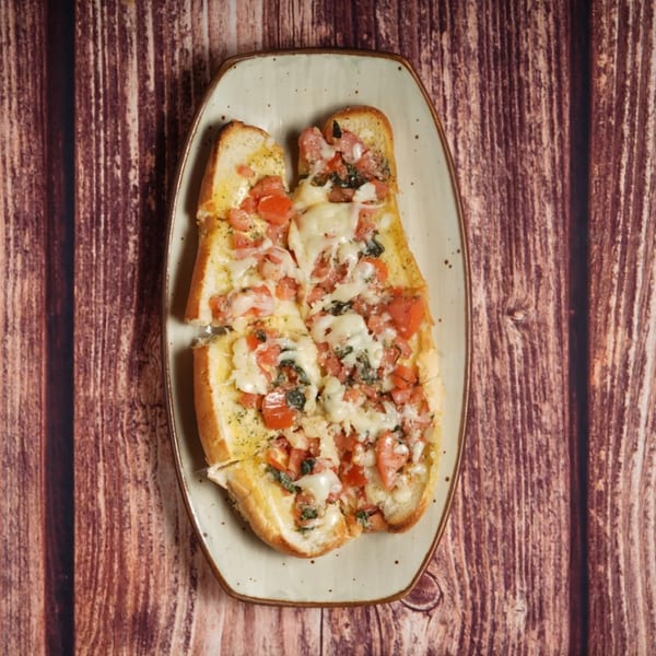 Billito's Italian Restaurant's bruschetta, topped with melted cheese, diced tomatoes, and herbs on a plate.
