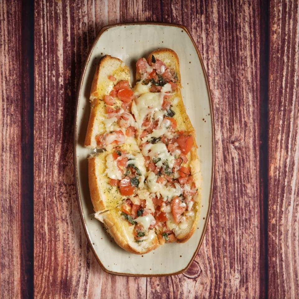 Billito's Italian Restaurant's bruschetta, topped with melted cheese, diced tomatoes, and herbs on a plate.