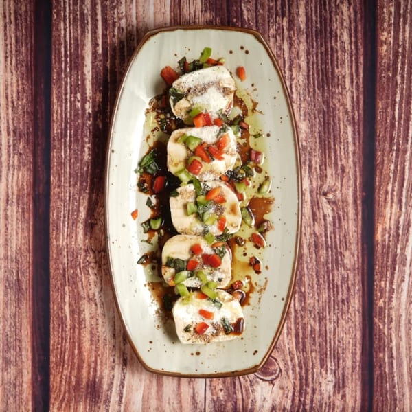 Four pieces of Billito's Italian Restaurant's mozzarella, topped with diced tomatoes, basil, and balsamic glaze.